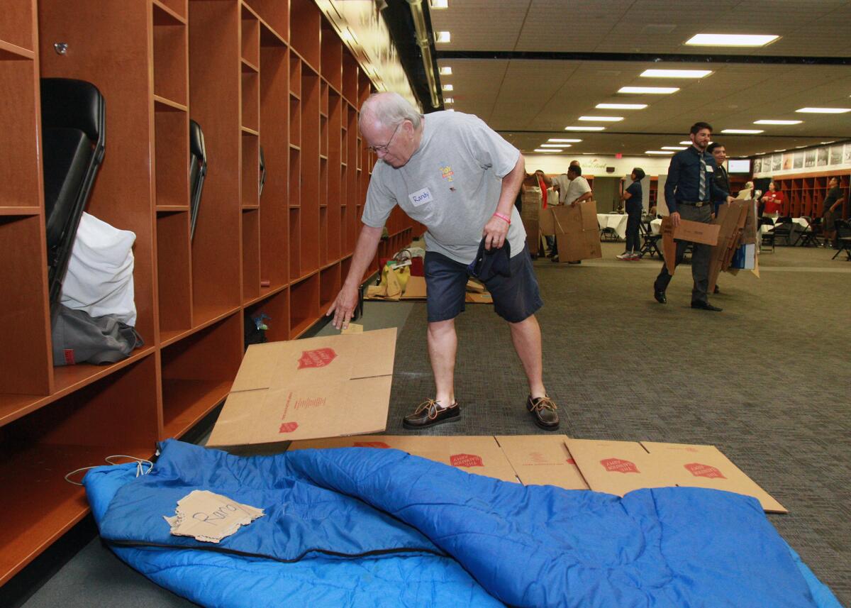 Randy Slaughter, of Glendale, puts "better" cardboard on his sleeping space at the Rose Bowl for the Salvation Army's Homeless Sleep Out Los Angeles on Thursday, June 30, 2016.