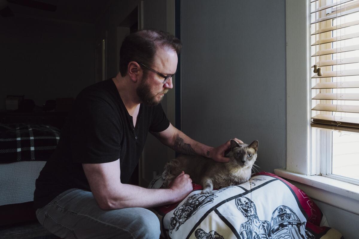 A man pets a cat.