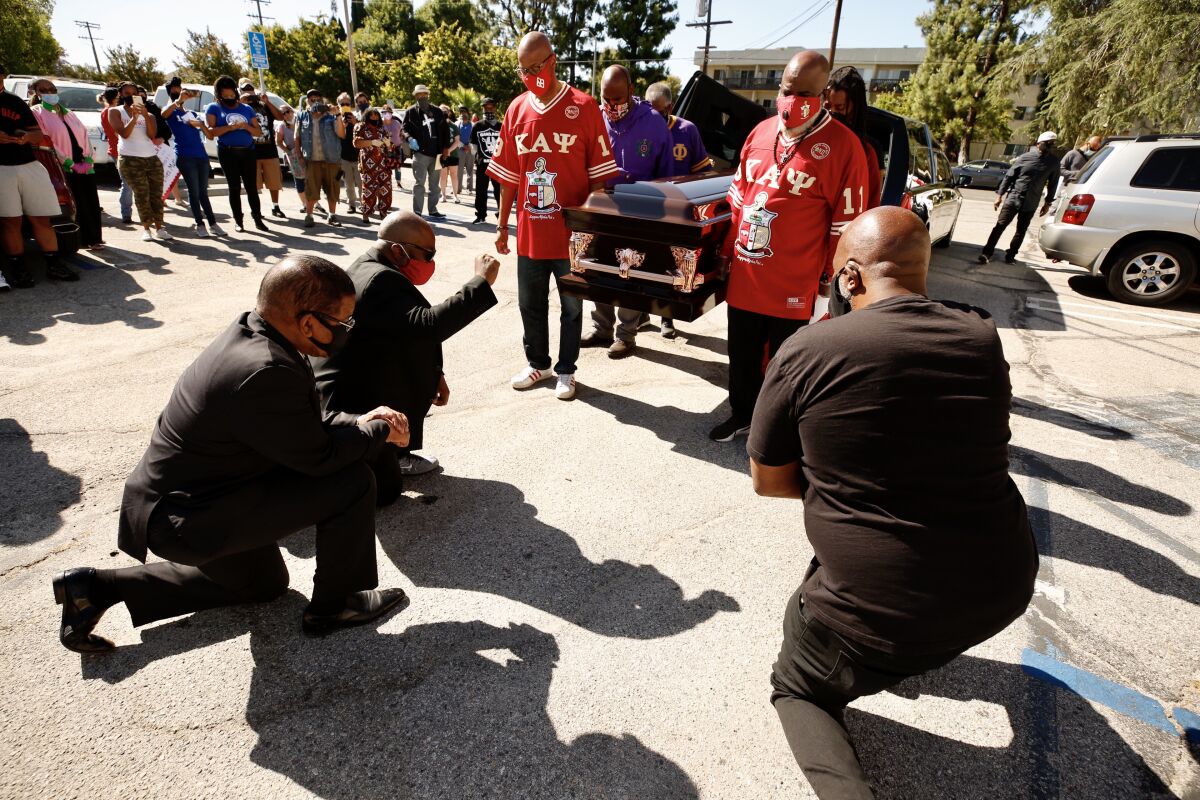 Pastors Dewayne Winrow and James Thomas kneel as pallbearers carry an empty casket in memory of George Floyd in Los Angeles.