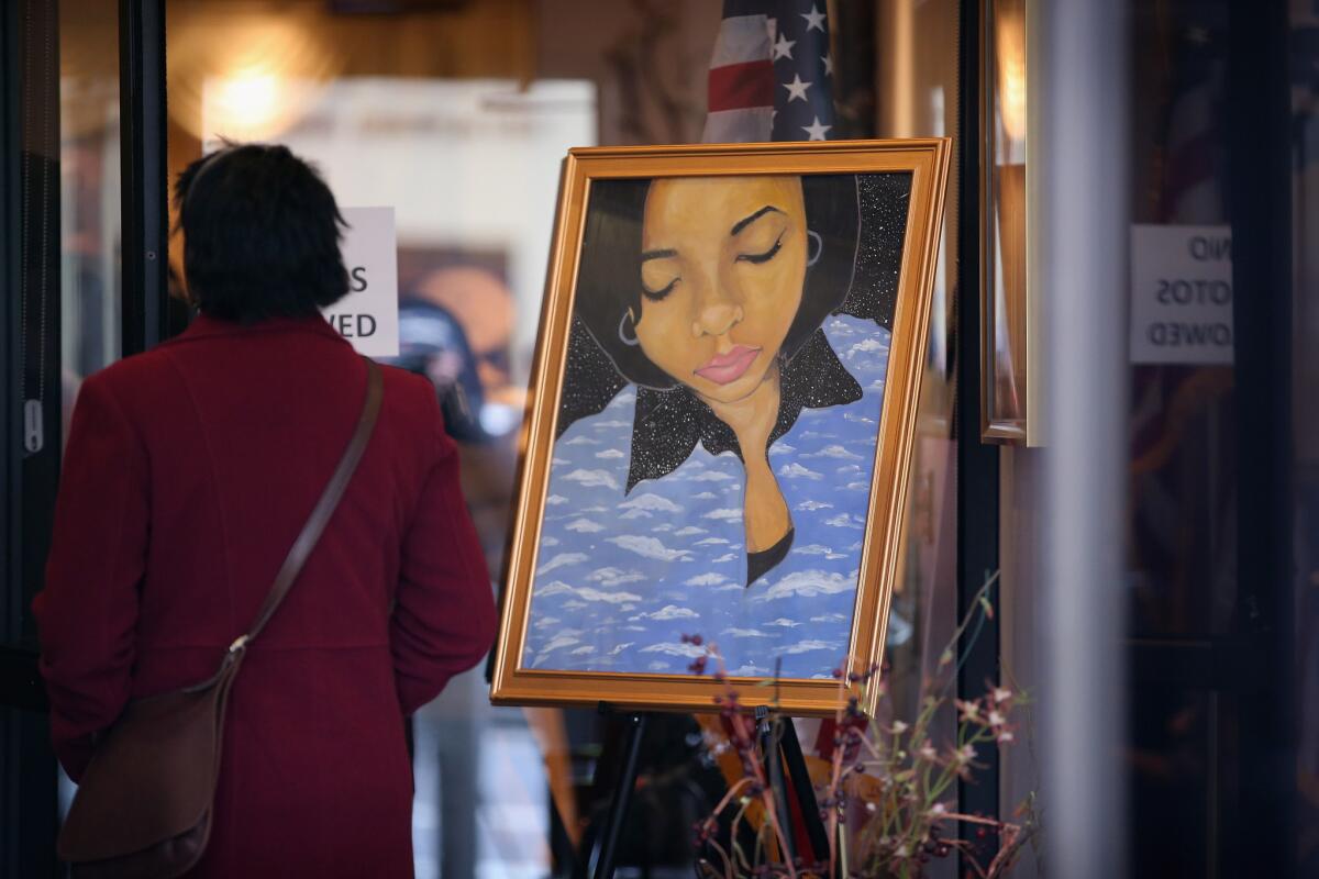 A mourner stands next to a painting of 15-year-old Hadiya Pendleton, placed at the entrance of the Calahan Funeral Home during her wake in Chicago.