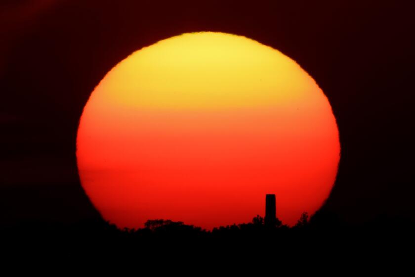 FILE - In this Friday, June 26, 2020 file photo, the sun sets behind a smokestack in the distance in Kansas City, Mo. According to a World Meteorological Organization forecast for the next five years, released on Thursday, May 27, 2021, it'll likely be so hot that there's a 40% chance in the next few years that the globe will push past the temperature limit set by the Paris climate agreement. (AP Photo/Charlie Riedel, File)