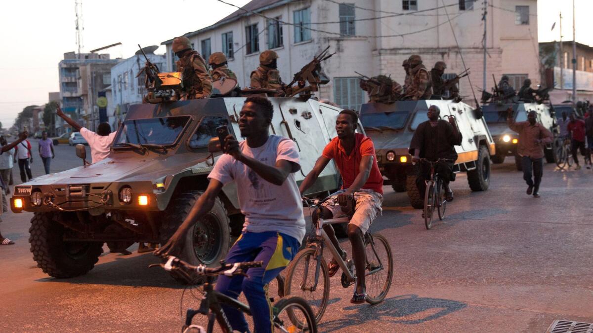 People cheer as Senegalese ECOWAS troops patrol outside the State House in the Gambian capital of Banjul on Jan. 22, 2017, one day after defeated President Yahya Jammeh went into exile.