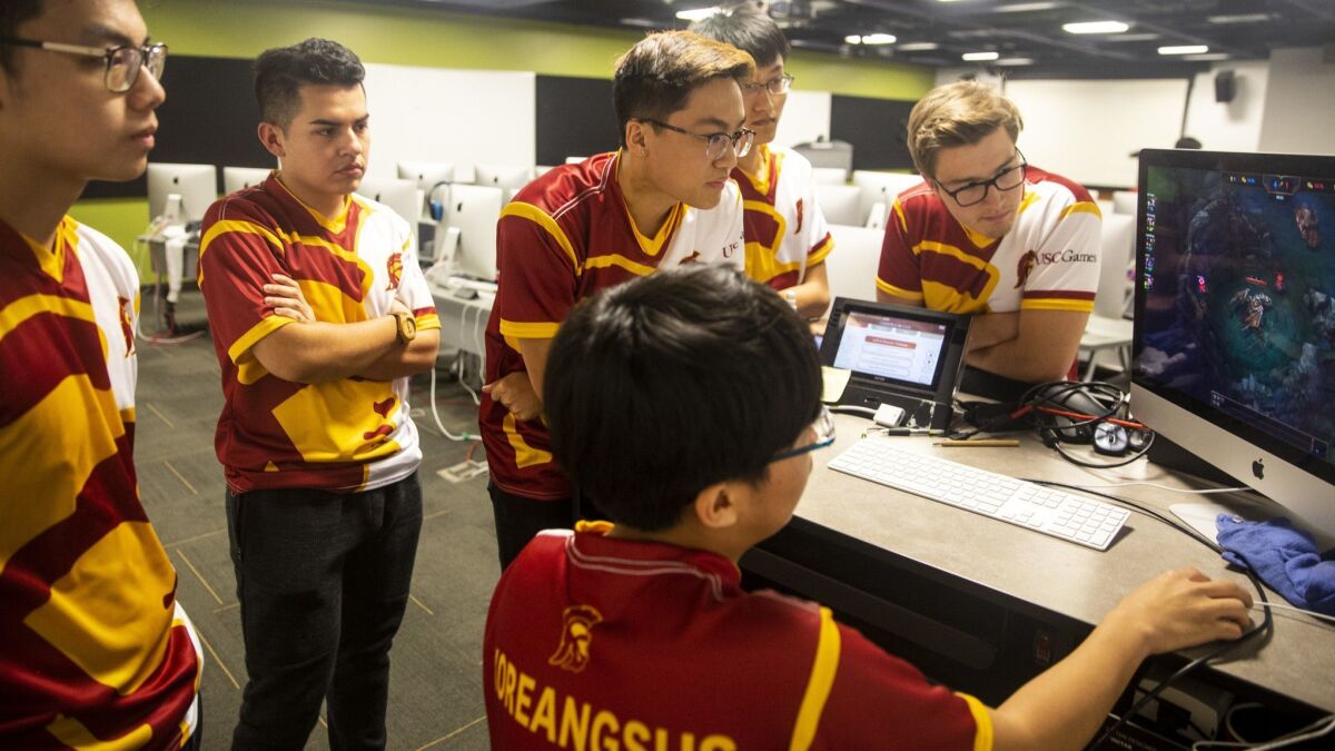 Michael Ahn, center, goes over a replay of his team's last match, while team members Duc Minh Nguyen, Ulysses Quesada, William Huang, Jonathan Chai and Jack Johnson look on.