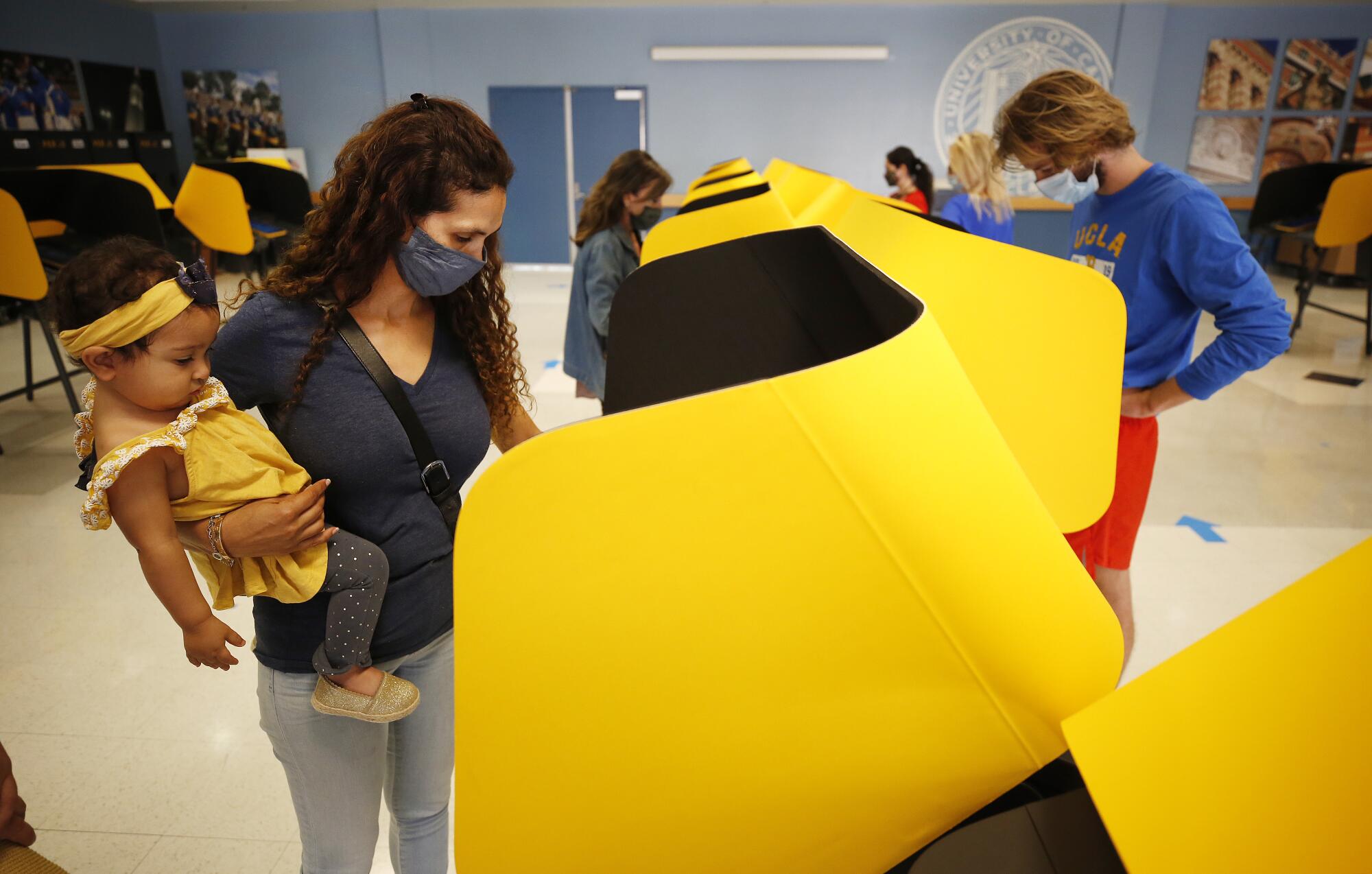 A mother holds her young daughter while voting