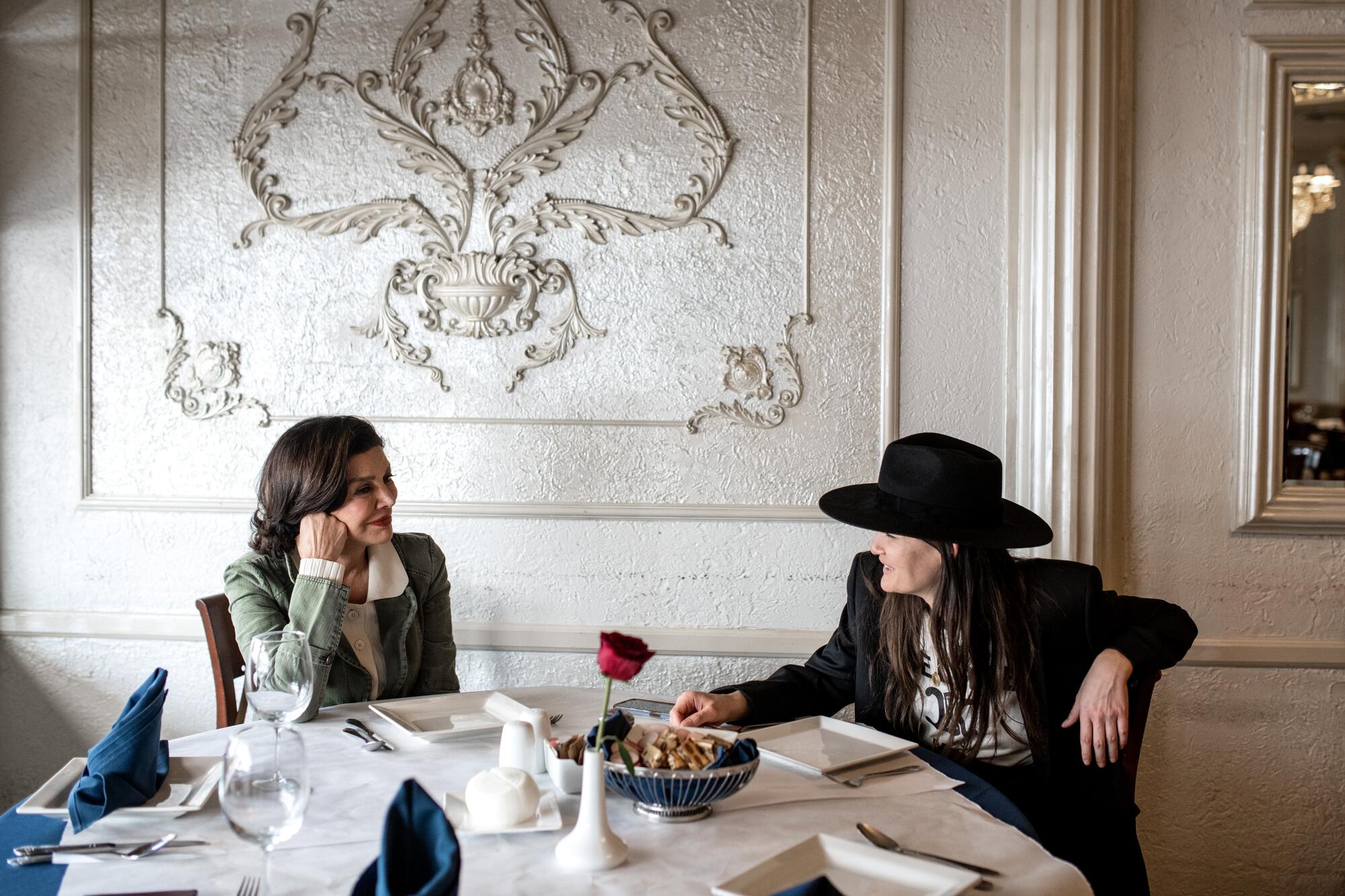 two women sit and look at each other at a restaurant table