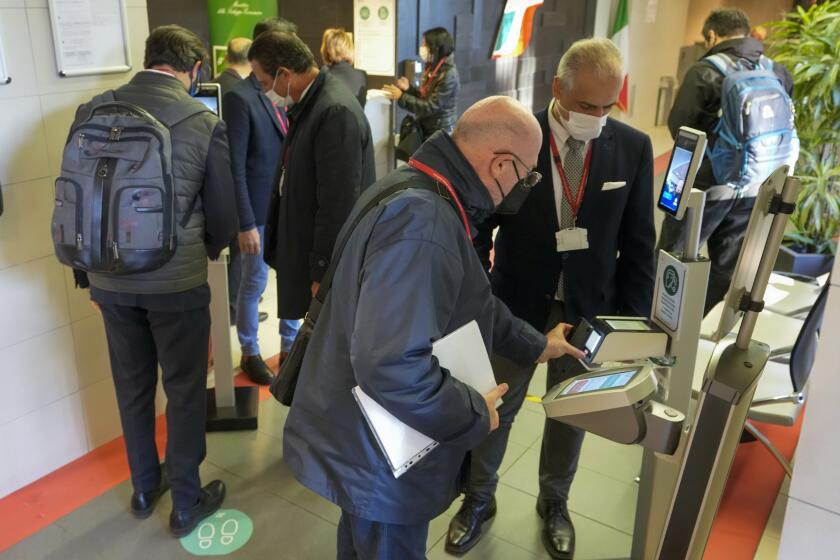 Employees have their certification checked as Italy's new “Green Pass” vaccination requirement for employees to enter their offices became mandatory, at the Trenitalia, Italian train company offices, in Rome, Friday, Oct. 15, 2021. From Friday, certification is required for public and private workplaces. Both employees and employers risk fines if they don’t comply. Public sector workers can be suspended if they show up five times without a Green Pass. The pass is already required in Italy to enter museums, theaters, gyms and indoor restaurants, as well as to take long-distance trains and buses or domestic flights. The passes show that a person has had least one COVID-19 vaccine dose, or recovered from the virus in the last six months, or has tested negative in the last 48 hours. (AP Photo/Andrew Medichini)