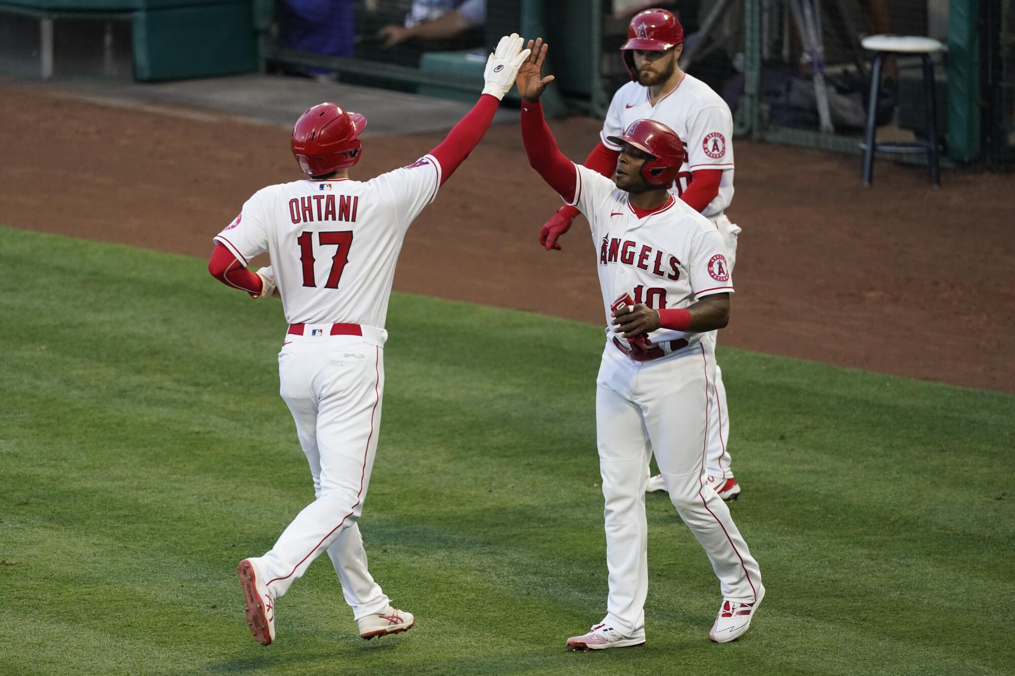 Angels teammates Shohei Ohtani, left, and Justin Upton celebrate after scoring off of a double hit by Anthony Rendon.