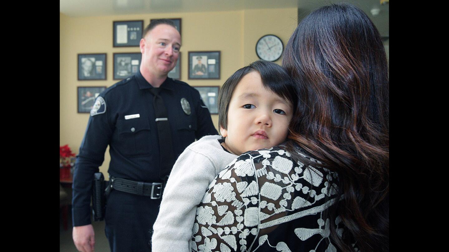 Looking sleepy, Clayton Cha, 3, rests his head on his mother Jennifer Cha's shoulder as she talks with Glendale police officer James Colvin at the Glendale Police Department on Thursday, Jan. 22, 2016. Last April, Colvin was the first on the scene to treat then 2-year-old Clayton, who had fallen on his head from 22-feet onto concrete.
