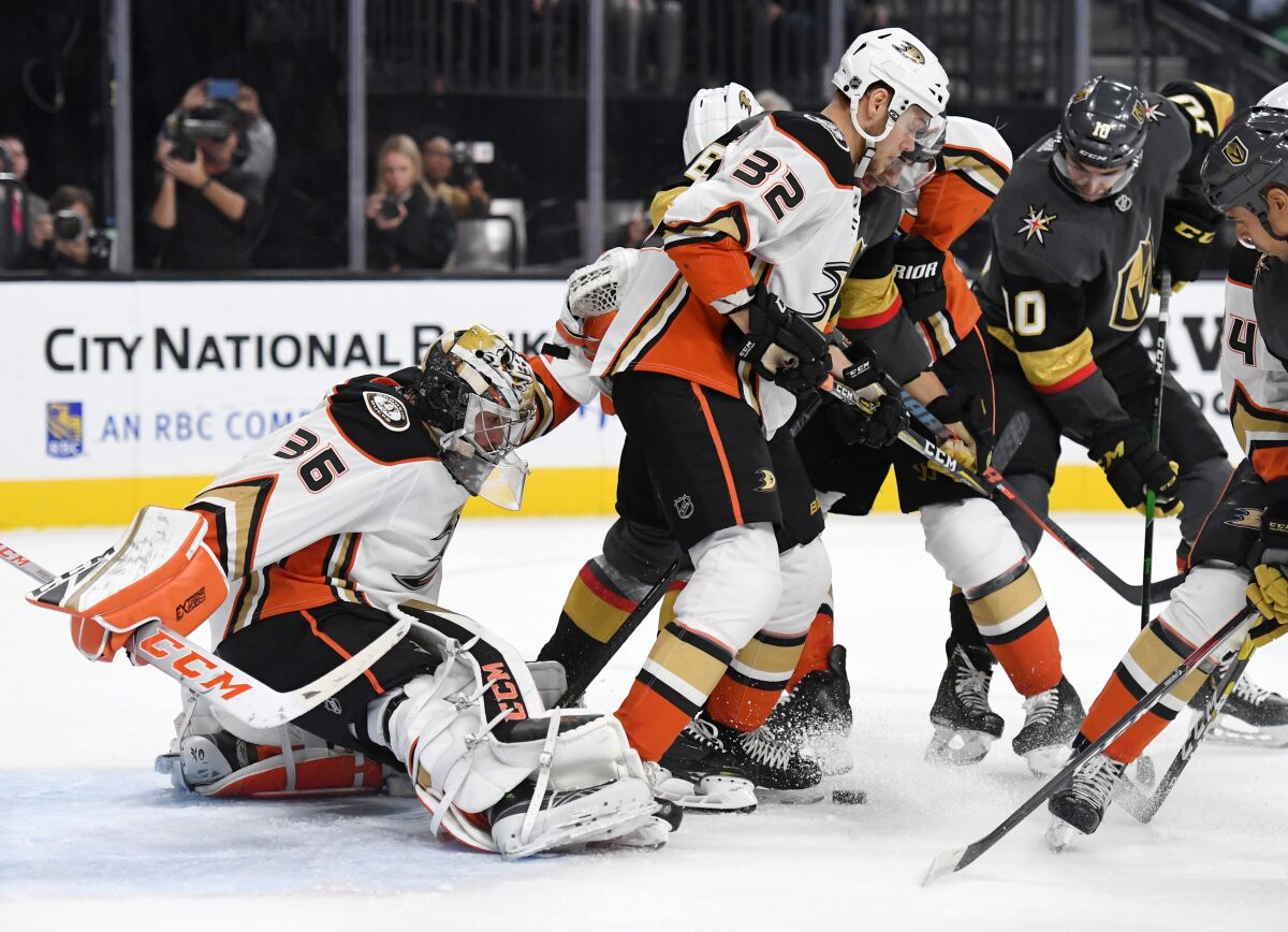 Ducks goalie John Gibson and defenseman Jacob Larsson, center, try to keep the puck out of the net.