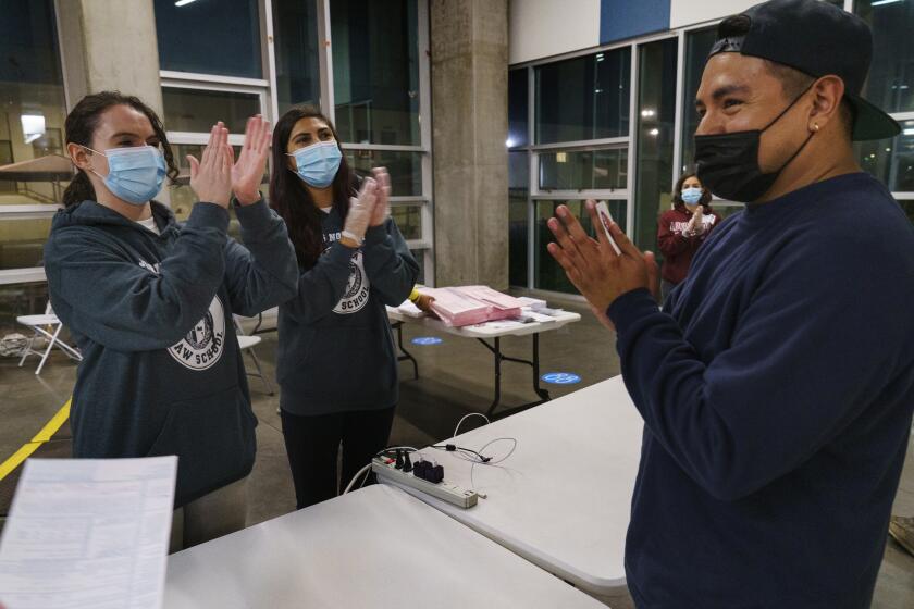 Loyola Law School students, from left, Laura Rodi, Victoria Bonds, and Kathy Feeney, far right, congratulate first time voter Hector Escobar Solis, who got a provisional ballot just a few minutes before the closing of the polling place at the Los Angeles City College in Los Angeles, on Tuesday, Nov. 3, 2020. Joe Biden won California and its 55 electoral votes Tuesday, tightening the Democrats' grip on the nation's most populous state. (AP Photo/Damian Dovarganes)