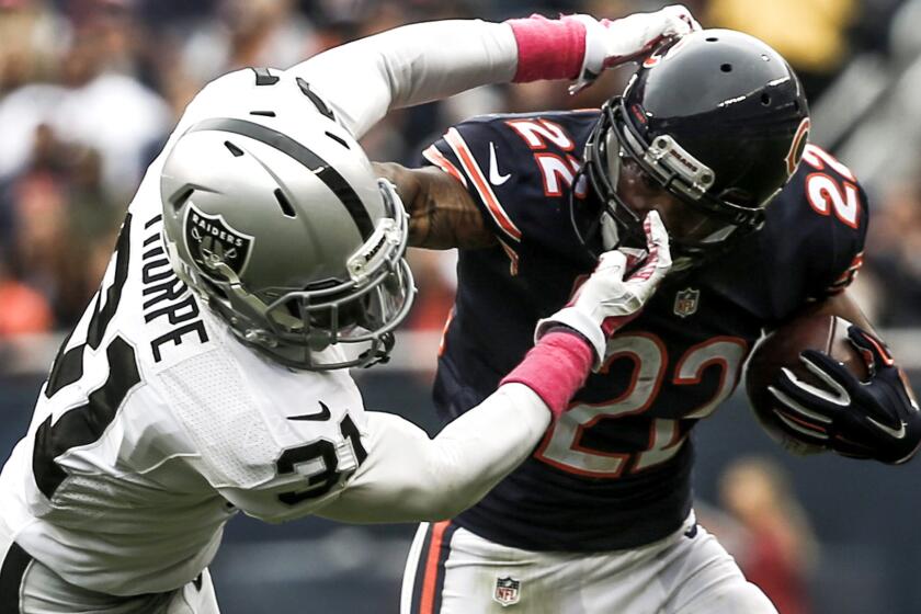 Bears running back tries to fend off a tackle by Raiders safety Neiko Thorpe in the first half Sunday.