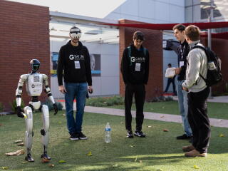 Two people handle a cleaning service humanoid by Gatlin Robotics.