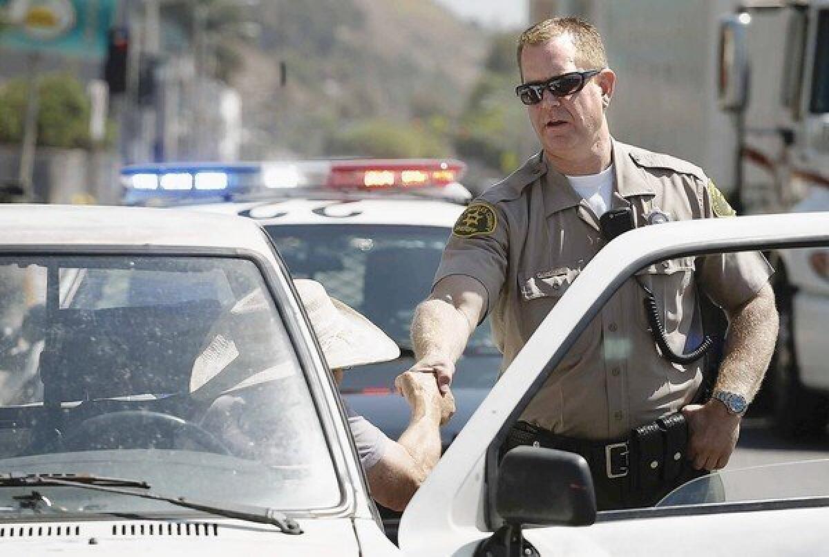 David Huelsen, a traffic detective with the L.A. County Sheriff's Department, interacts with a motorist on Pacific Coast Highway earlier this month. Huelsen is one of the lawmen that the Sheriff's Department has equipped with a digital camera in an effort to cut down on the number of innocent people jailed after being mistaken for wanted criminals.