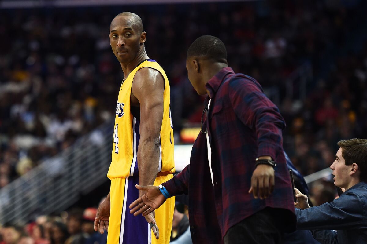 Lakers' Kobe Bryant, left, shakes hands with a fan during the first half against the New Orleans Pelicans on Thursday.