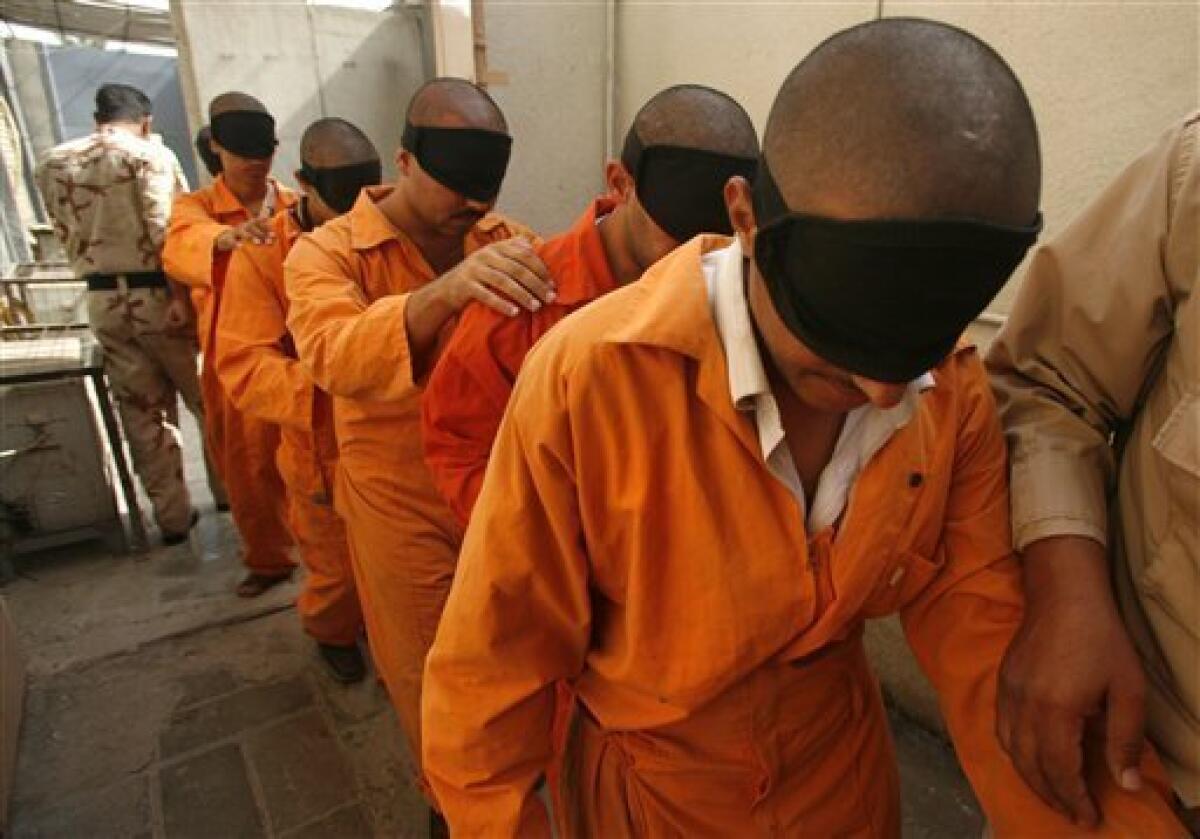 In this Aug. 11, 2007 file photo, blindfolded prisoners are taken for questioning at the Iraqi National Police Detention Center in the Kazimiyah neighborhood of North Baghdad, Iraq. Iraqi officials outraged by the abuse of prisoners at the U.S.-run Abu Ghraib prison are dealing with a prison scandal of their own as allegations continue to surface about years of torture and mistreatment inside Iraq's own lockups. (AP Photo/Petr David Josek, File)
