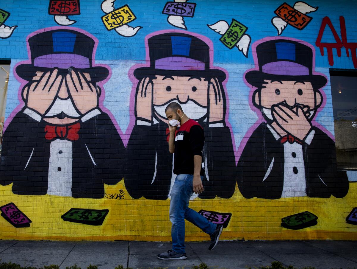 A person in a mask walks in front of a mural