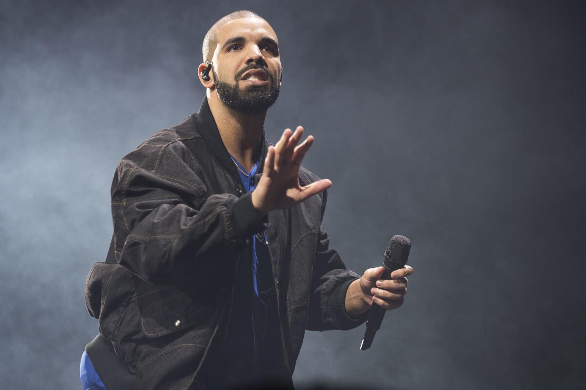 Drake holds a microphone while performing onstage