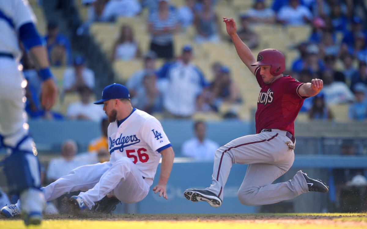 Dodgers reliever J.P. Howell lands on home plate and prepares to tag out Diamondbacks catcher Jordan Pacheco after an errant pitch in the 13th inning Sunday.