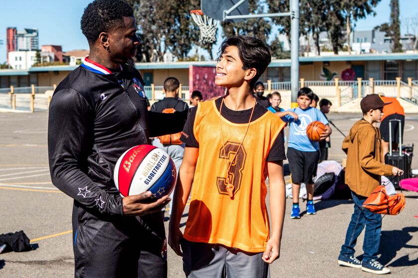San Diego, CA - January 31: Arden Pala, 13, left, smiles as he chats with Harlem Globetrotter Flip White at Perkins K-8 School on Tuesday, Jan. 31, 2023 in San Diego, CA. Arden created a basketball league at the school that lacked a PE instructor for several months. The basketball league also helped children in find an outlet. Harlem Globetrotters came to surprise Arden and praise his work in the community.(Meg McLaughlin / The San Diego Union-Tribune)