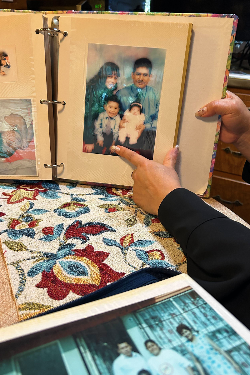 A hand points to a family photo in an old album