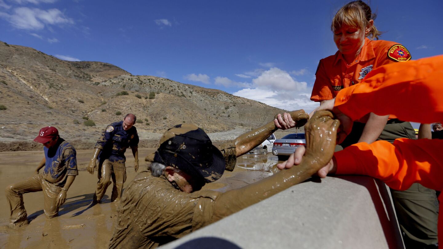 TV cameraman Monte Duarte is helped off California 58 after he became stuck in the mud and was assisted by California Highway Patrol Officer Edward Stewart and photographer Travis Geske, background.