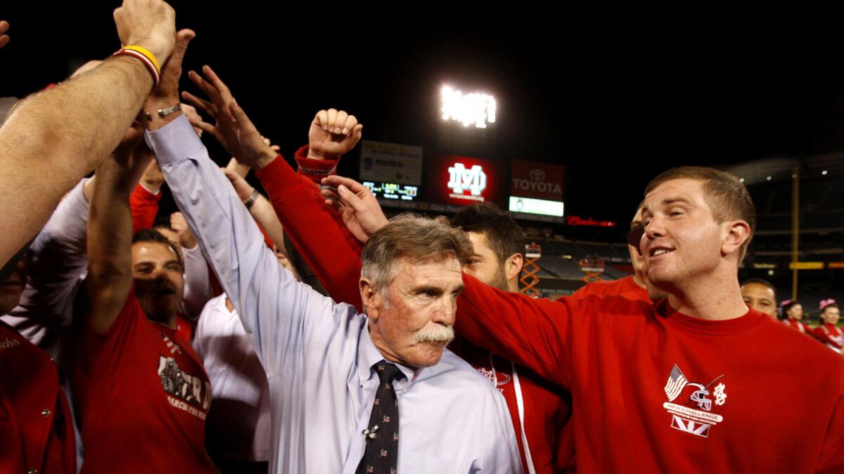 Coach Bruce Rollinson celebrates with alumni after Mater Dei defeated Servite, 28-21, on Oct. 11, 2013, at Anaheim Stadium.
