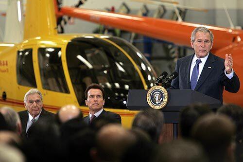 President George W. Bush addresses employees at the Robinson Helicopter Co. in Torrance. Joining him are Frank Robinson, left, founder and president of the firm, and Gov. Arnold Schwarzenegger.