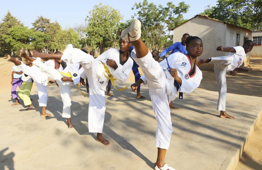 Natsiraishe Maritsa, second right, goes through taekwondo kicking drills during a practice session with young boys and girls in the Epworth settlement about 15 km southeast of the capital Harare, Saturday Nov. 7, 2020. In Zimbabwe, where girls as young as 10 are forced to marry due to poverty or traditional and religious practices, a teenage martial arts fan 17-year old Natsiraishe Maritsa is using the sport to give girls in an impoverished community a fighting chance at life. (AP Photo/Tsvangirayi Mukwazhi)