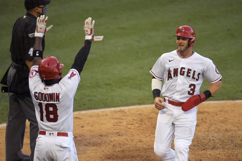 Los Angeles Angels' Taylor Ward, right, scores on a sacrifice fly hit by David Fletcher as Brian Goodwin (18) celebrates during the sixth inning of a baseball game against the Houston Astros, Saturday, Aug. 1, 2020, in Anaheim, Calif. (AP Photo/Mark J. Terrill)