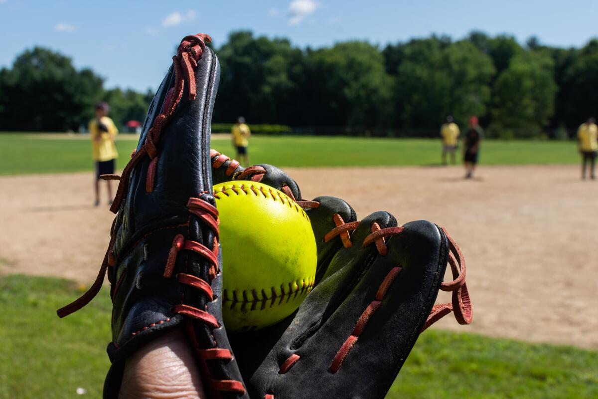 Softball glove in front of a softball field.