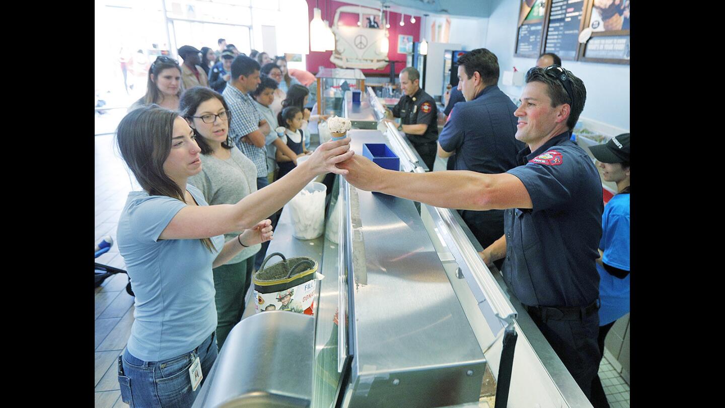 Burbank Firefighter Mike Carey hands Kayla Mackey, of Los Angeles, an ice cream cone at Ben & Jerry's in Burbank on Tuesday, April 10, 2018. The Burbank Fire Department will be handing out single scoops of ice cream as part of the 40th annual Ben & Jerry's Free Cone Day. As well, people can donate to the Muscular Dystrophy Association.