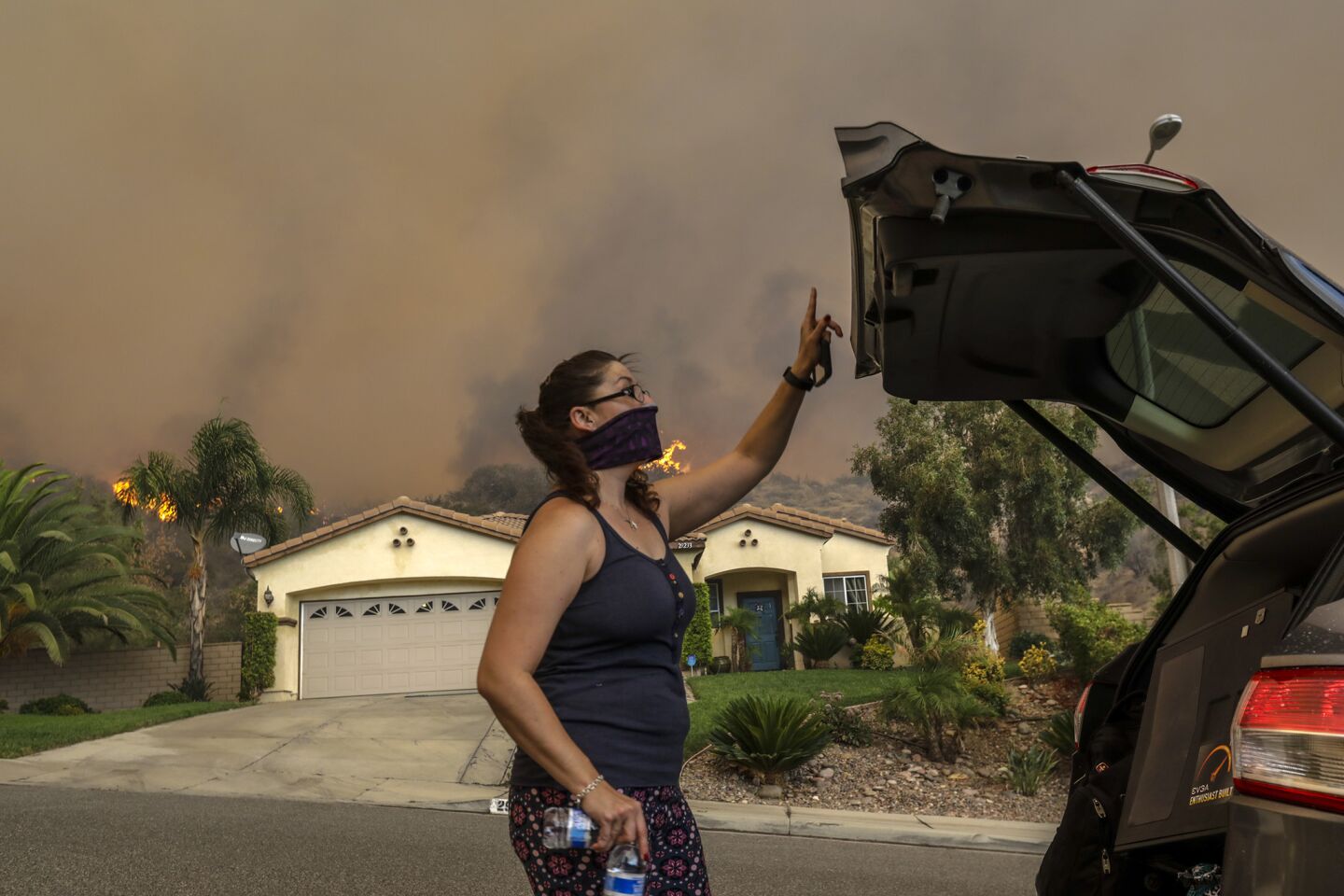 Stephanie Caceres packs her belongings into her car as the Holy fire approaches homes on Sandpiper Drive in Lake Elsinore.