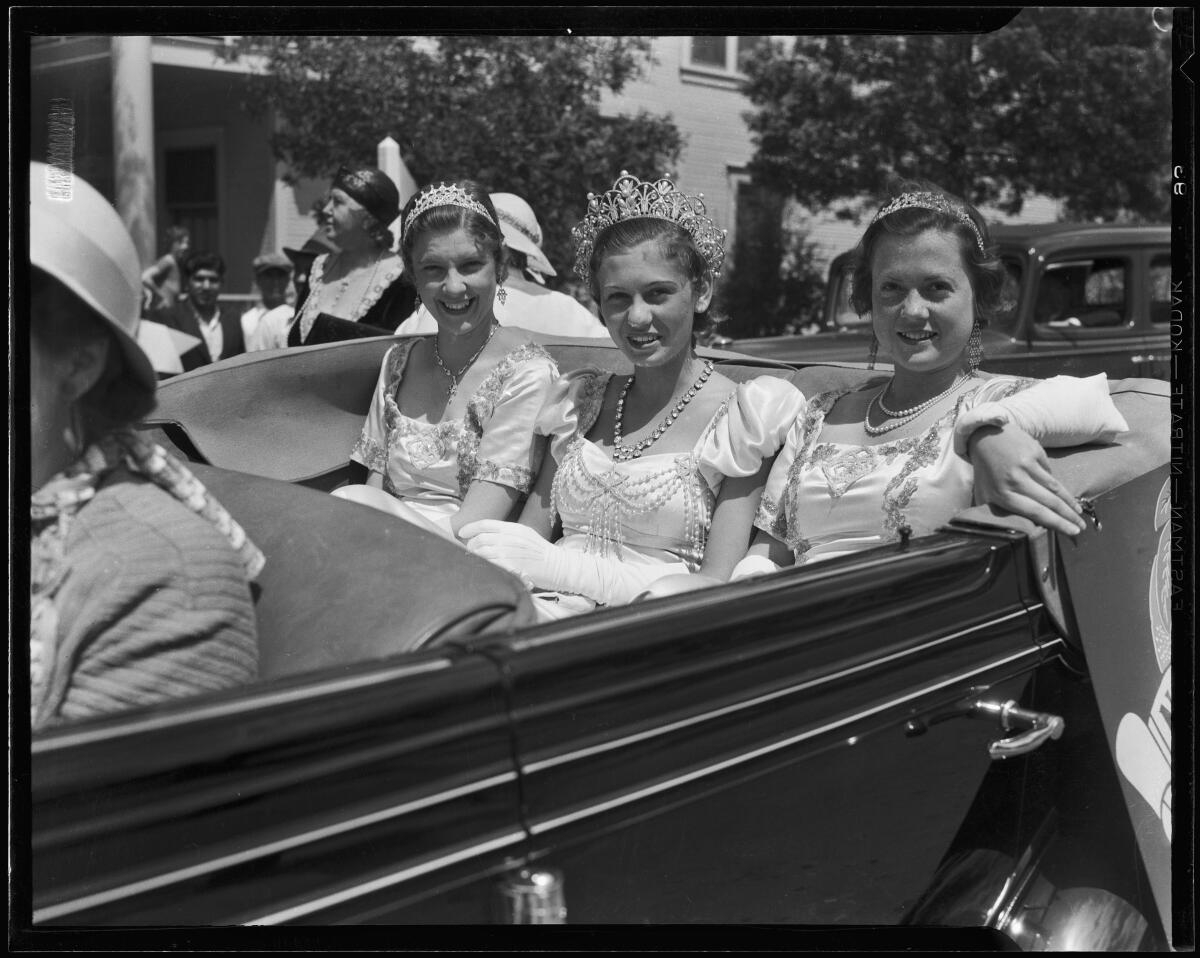 Three women ride in the back of a convertible 