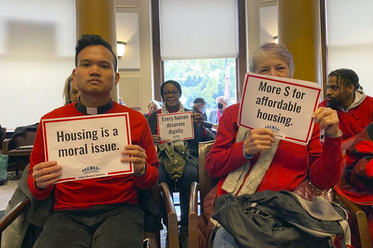 Members of the Leaven Community Land & Housing Coalition attend a Portland City Council Meeting on Thursday, Nov. 3, 2022, in Portland, Ore., to oppose a resolution that would ban street camping and create designated areas for homeless camping. The resolution has sparked fierce debate in the city. (AP Photo/Claire Rush)