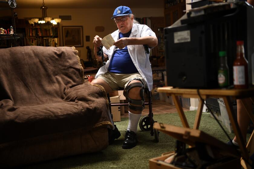 SAN DIMAS, CALIFORNIA JULY 22, 2020-Conrad Munatones goes through some old photos at his home in San Dimas. Munatones was in the Dodgers organization as a catcher before becoming a teacher. (Wally Skalij/Los Angeles Times)