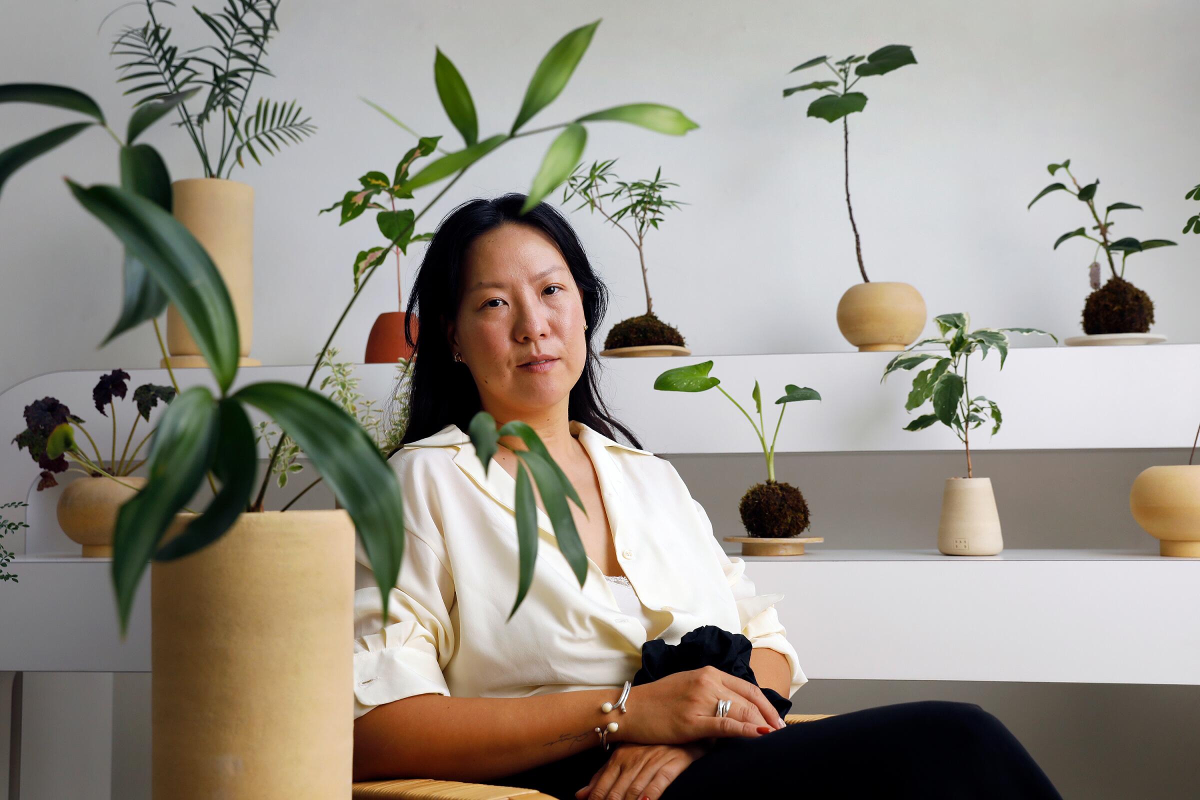Yunice Kang of Sanso, seated, surrounded by her rare plant designs.
