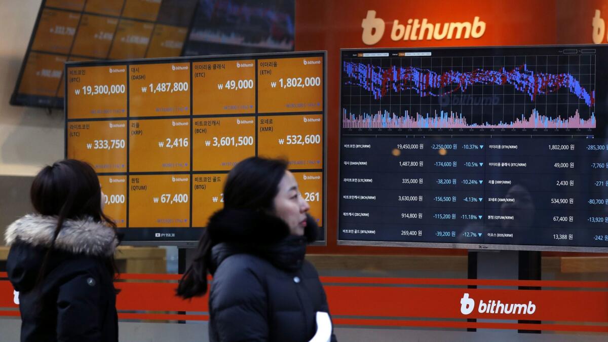 People look at monitors displaying cryptocurrency values at Bithumb, one of South Korea's biggest digital currency exchanges, in Seoul.