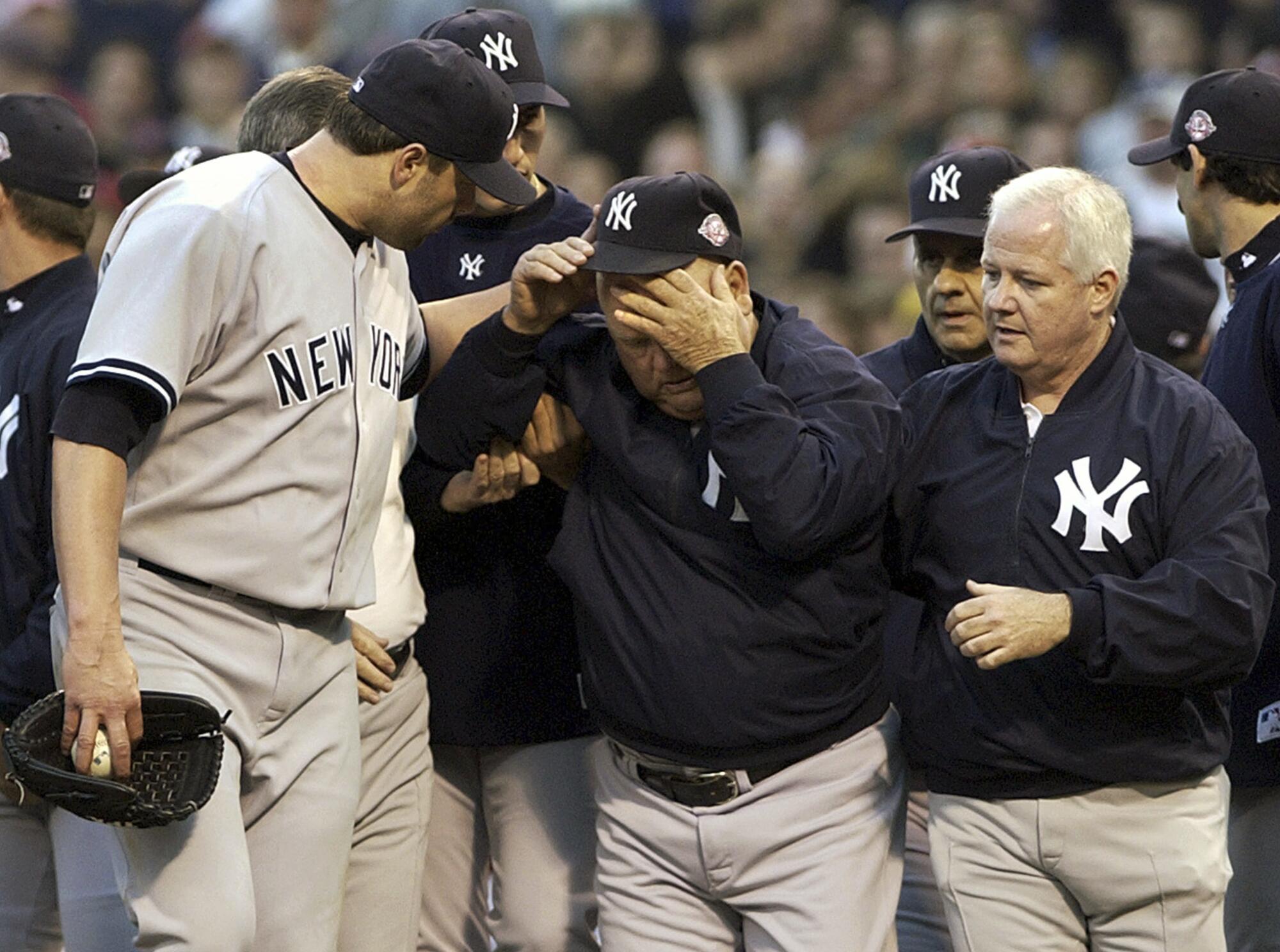 New York Yankees' Roger Clemens looks after bench coach Don Zimmer, who had been thrown to the ground by  Pedro Martinez.