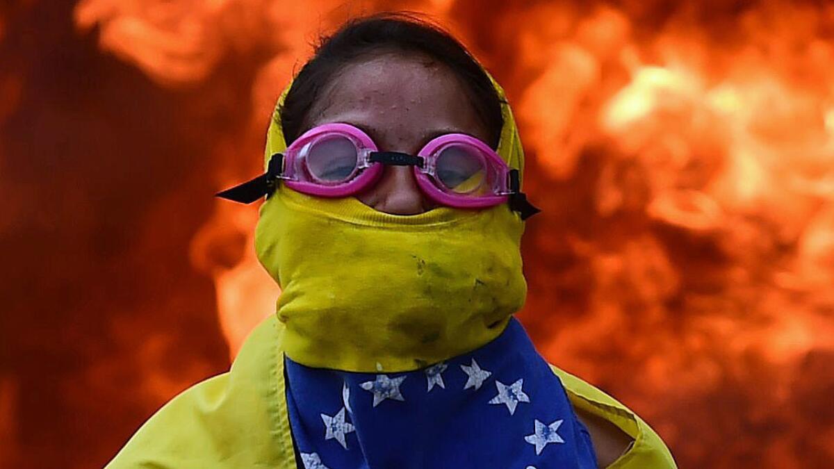 TOPSHOT - A Venezuelan opposition activist is backdropped by a burning barricade during a demonstration against President Nicolas Maduro in Caracas, on April 24, 2017. Protesters rallied on Monday vowing to block Venezuela's main roads to raise pressure on Maduro after three weeks of deadly unrest that have left 21 people dead. Riot police fired rubber bullets and tear gas to break up one of the first rallies in eastern Caracas early Monday while other groups were gathering elsewhere, the opposition said. / AFP PHOTO / Ronaldo SCHEMIDTRONALDO SCHEMIDT/AFP/Getty Images ** OUTS - ELSENT, FPG, CM - OUTS * NM, PH, VA if sourced by CT, LA or MoD **