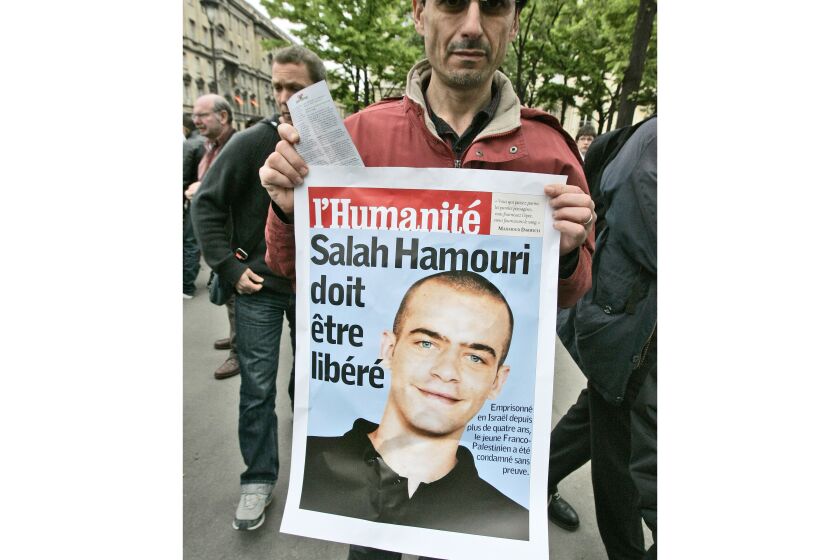 FILE - A member of a pro-Palestinian group holds a poster showing French-Palestinian Salah Hammouri, then detained in Israel after a sentencing by a military court, near the Foreign ministry in Paris to protest the visit of Israeli Foreign minister Avigdor Lieberman to his French counterpart, May 5, 2009. The placard reads "Salah Hammouri must be freed." Israel will have to wait to deport Hammouri to France for at least several weeks. Hammouri appeared at a court hearing near Tel Aviv, Tuesday, Dec. 6, 2022. No decisions were made, and another hearing was set for Jan. 1, 2023, said Dani Shenhar, one of his lawyers. (AP Photo/Francois Mori, File)