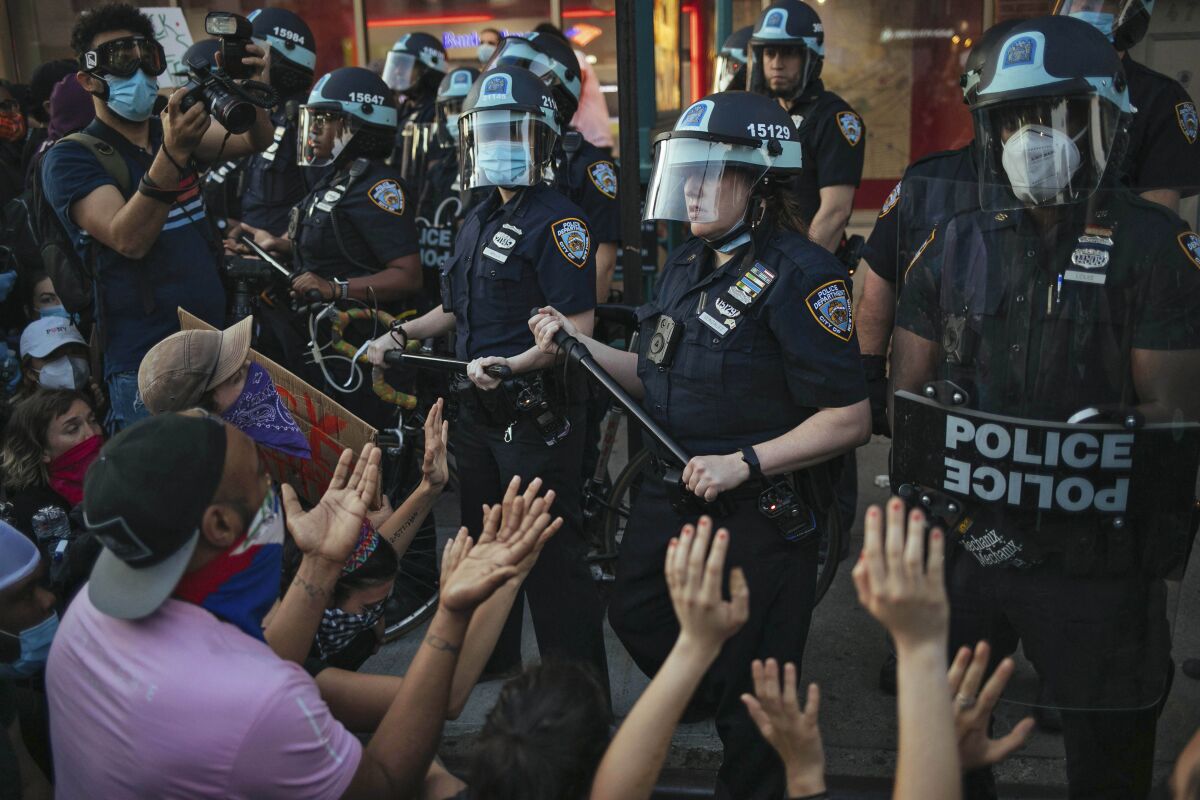 A line of police officers face protesters.