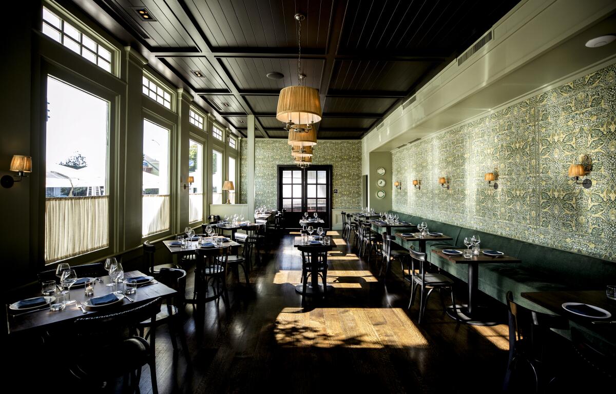 Tables are set for dinner in a room with boldly patterned wallpaper.