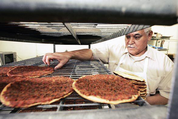 Francisco Rosales, who, with Jose Gonzales was given A. Partamian Bakery on West Adams Boulevard in West Los Angeles on the death of their boss, Leon Partamian. Here, he stacks up lahmajunes -- sometimes called Armenian pizzas -- after letting them cool on a rack