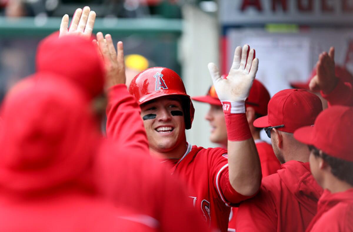 Angels teammates congratulate Mike Trout after he scored a run against the Astros on Sunday afternoon in Anaheim.