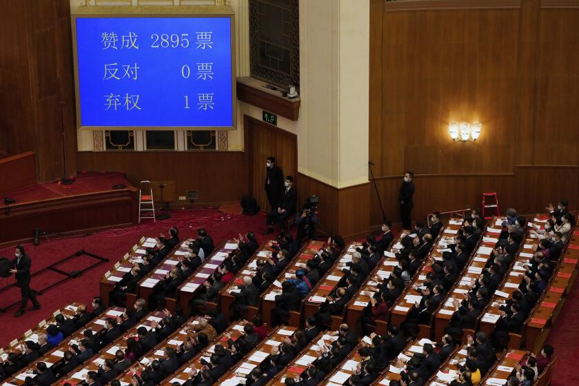 Delegates applaud near a screen showing number of votes for support of the plan to give a pro-Beijing committee power to appoint more of Hong Kong's lawmakers, during the closing session of the National People's Congress (NPC) at the Great Hall of the People in Beijing, Thursday, March 11, 2021. China's ceremonial legislature on Thursday endorsed the ruling Communist Party's latest move to tighten control over Hong Kong by reducing the role of its public in picking the territory's leaders. (AP Photo/Sam McNeil)