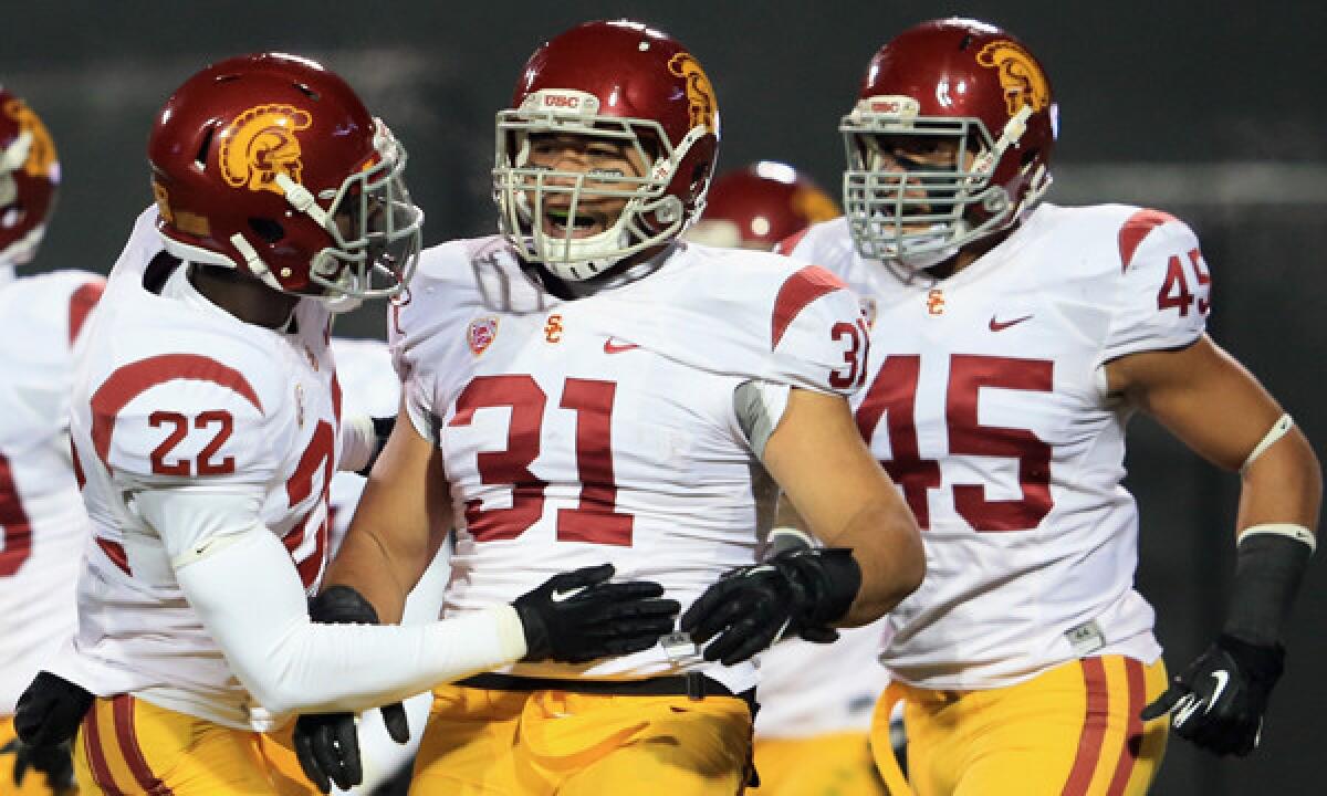USC's Soma Vainuku, center, is congratulated by teammate Leon McQuay III, left, after blocking a punt in a win over Colorado in November. The Trojans' trek to the Las Vegas Bowl hasn't been an easy one.