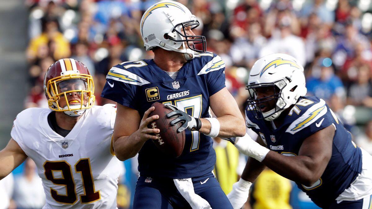 Chargers quarterback Philip Rivers, center, looks to pass with offensive tackle Russell Okung, right, blocking out Washington Redskins outside linebacker Ryan Kerrigan, left, during the first half on Sunday.
