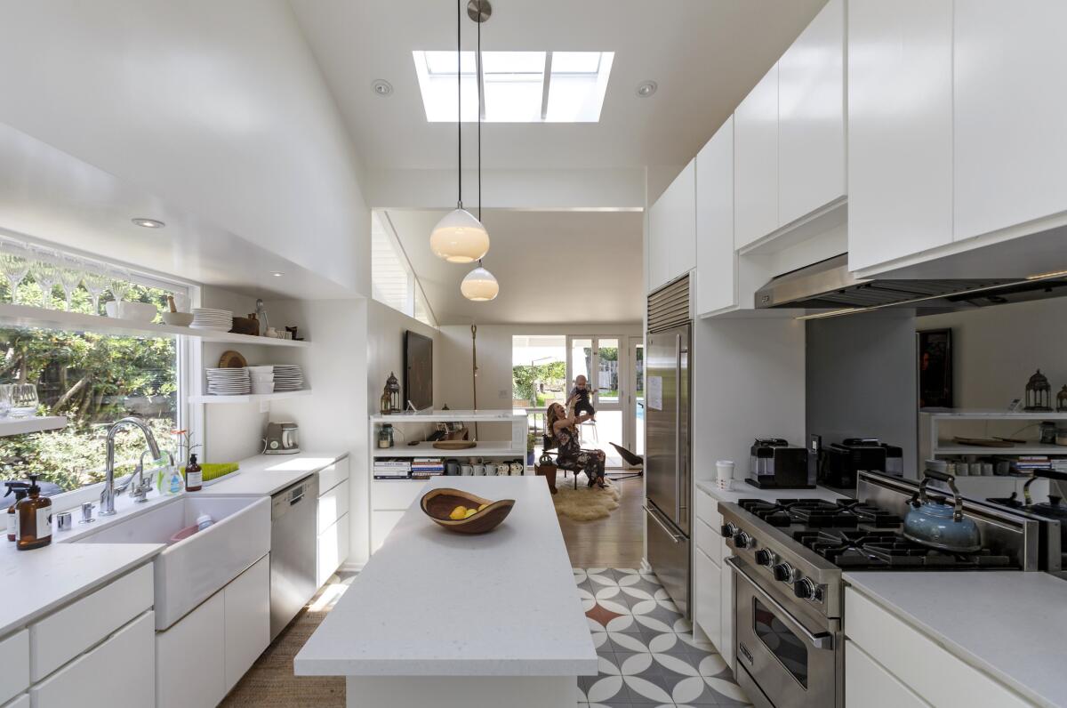 Working with architect John Frane, the couple redid the modest-sized kitchen, which was previously enclosed, and created a laundry room with an adjoining bathroom. The Caesarstone-topped center island, shown here, features hidden storage on either side.