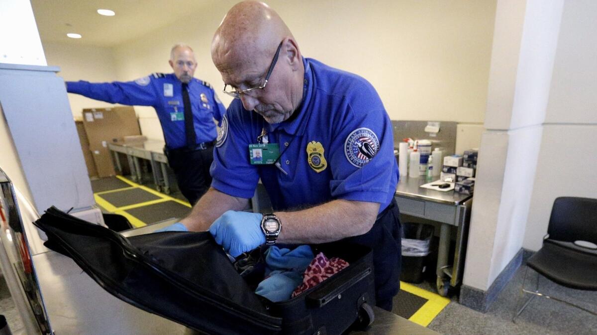 A TSA agent checks a bag at a security checkpoint area at Midway International Airport in Chicago. The American Civil Liberties Union has filed a lawsuit against the TSA, asking for information about the searches of electronic devices on domestic flights.