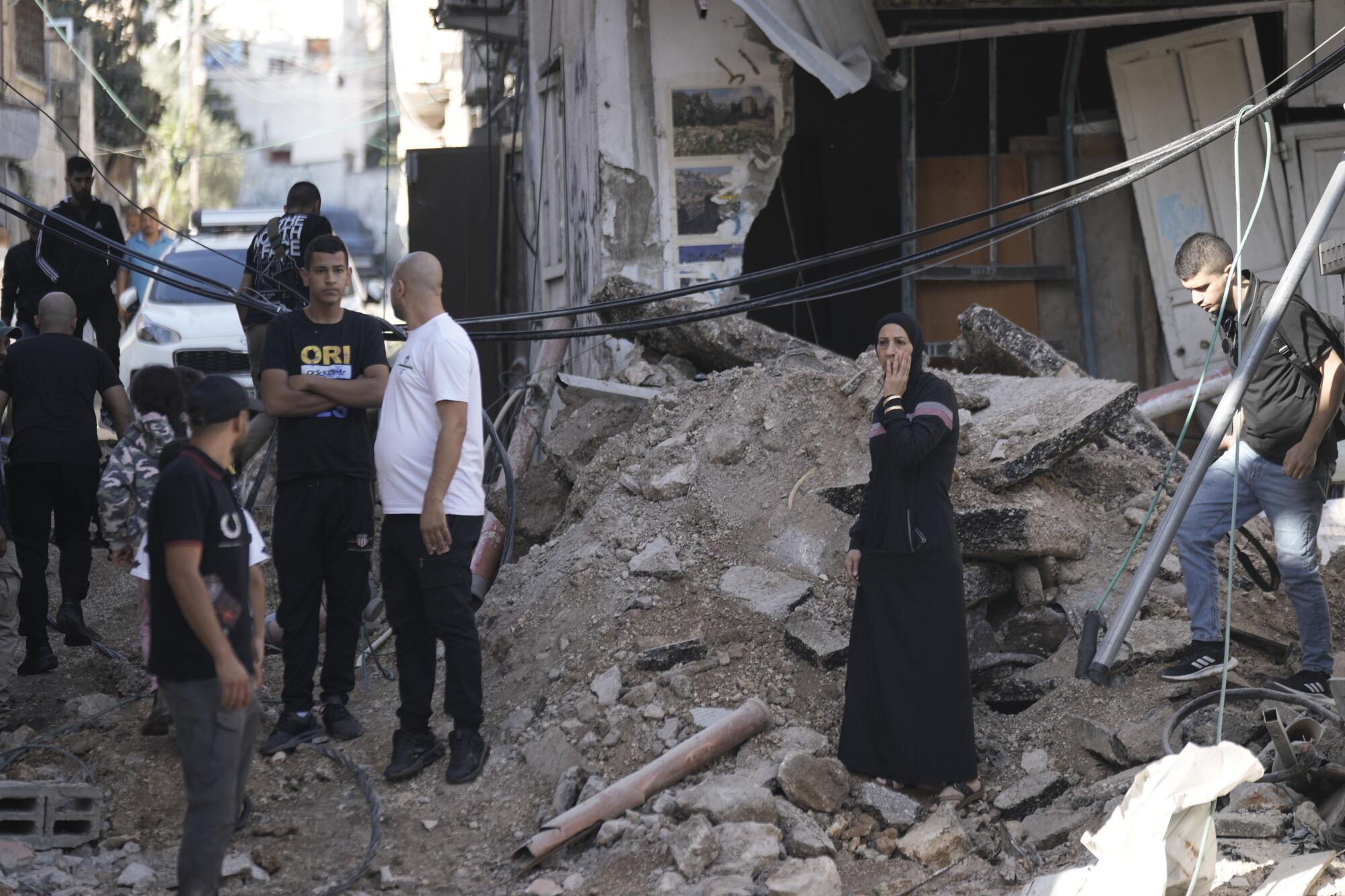 People looking at debris after an Israeli army raid on a Palestinian refugee camp in the West Bank.